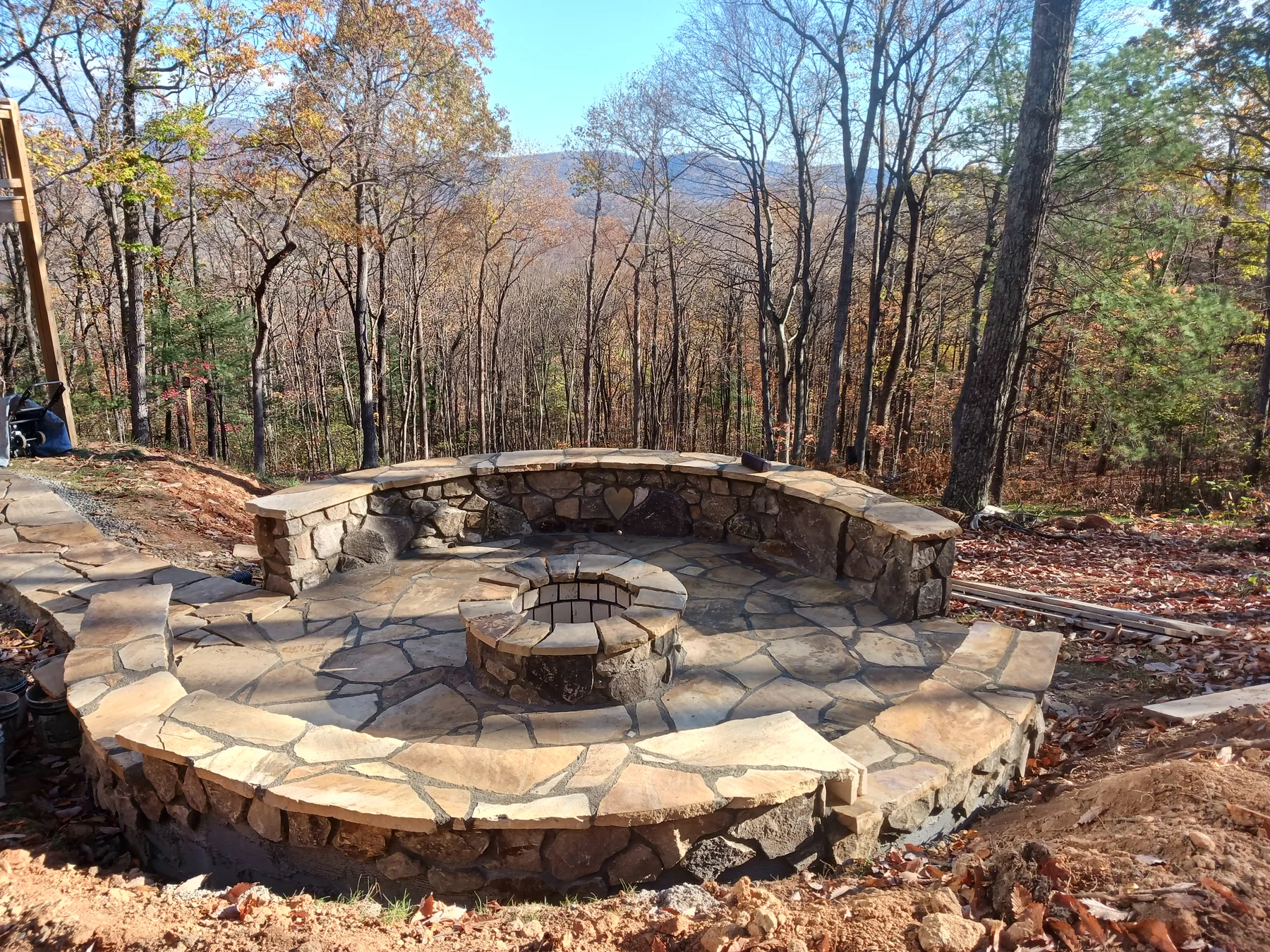 Rustic stone patio with curved stone seating surrounded by trees